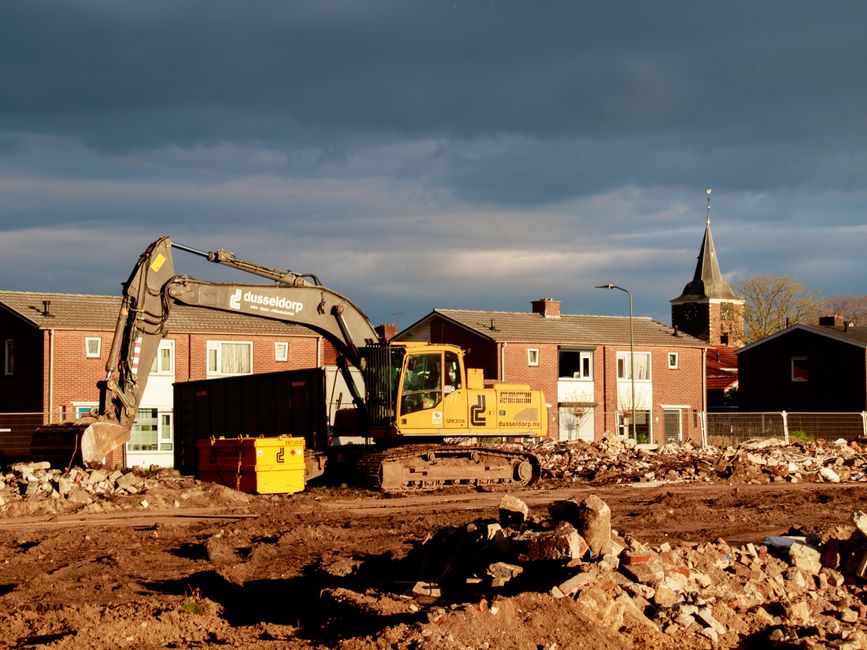 Pelleteuse et gravats sur un chantier de démolition au pied de maisons (photo d’illustration)